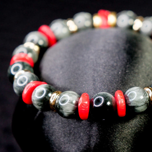 Bracelet with gray, red, and gold beads on a black background