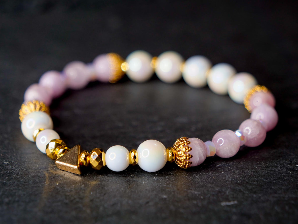 Elegant white, pink and gold beaded bracelet on a black stone surface