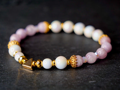 Elegant white, pink and gold beaded bracelet on a black stone surface